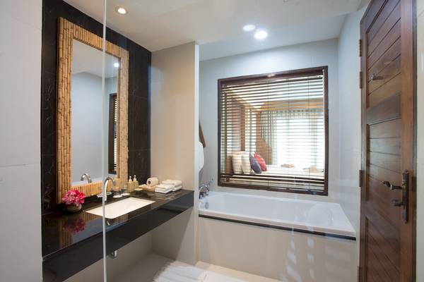 Badezimmer im Tup Kaek Sunset Beach Resort mit Badewanne, Waschbecken und Spiegel.