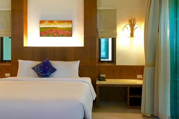 Hotelzimmer im Tup Kaek Sunset Beach Resort mit Bett, Kissen und Gemälde an der Wand.
