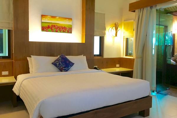 Schlafzimmer im Tup Kaek Sunset Beach Resort mit einem Bett, Kissen und einem Gemälde an der Wand.