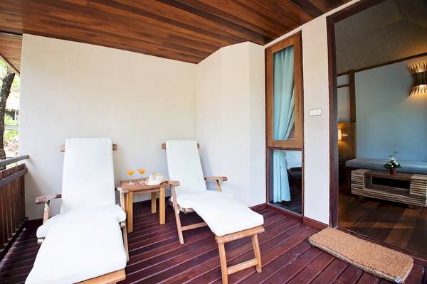 Balkonbereich des Tup Kaek Sunset Beach Resorts mit zwei weißen Lounge-Stuhle und einem Tisch.