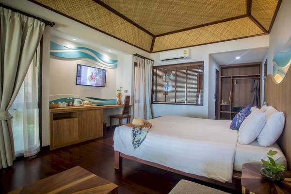 Innenansicht eines Hotelzimmers im Tup Kaek Sunset Beach Resort mit Bett, Fernseher und Schreibtisch