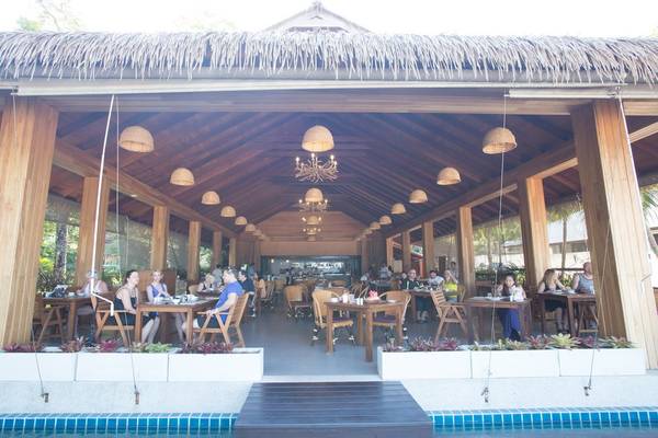 Terrasse des Tup Kaek Sunset Beach Resorts mit Gästen an Tischen.