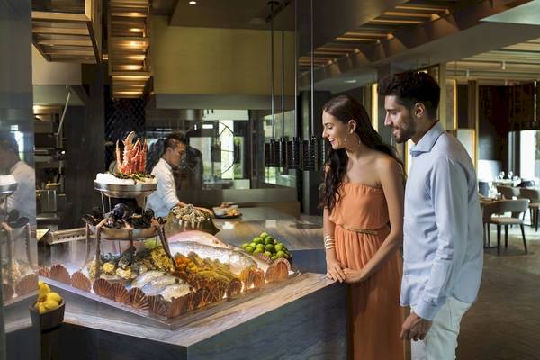 Ein Paar steht am Buffet-Tisch im Saadiyat Rotana Resort & Villas und betrachtet Meeresfrüchte.