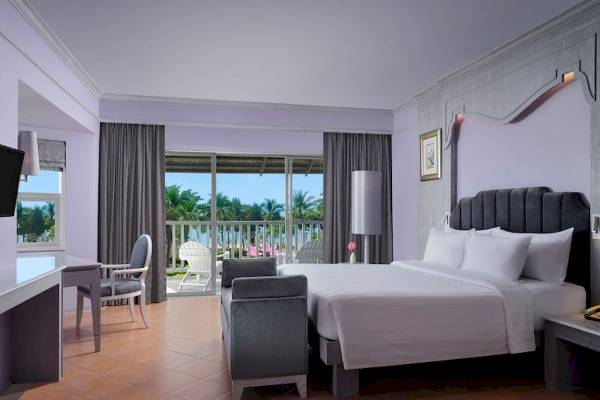 Hotelzimmer im Aonang Villa Resort mit einem großen Bett, einem Schreibtisch und einem Balkon mit Blick auf den Strand.