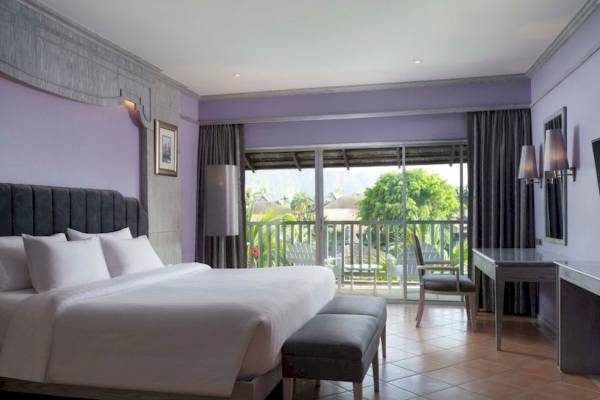 Schlafzimmer im Aonang Villa Resort mit großem Bett, Balkon und Ausblick auf Bäume.