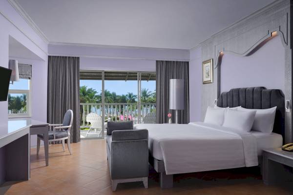 Schlafzimmer im Aonang Villa Resort mit Doppelbett, Sitzbereich, Schreibtisch und Blick auf die Terrasse.