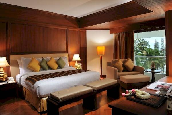 Ein elegantes Schlafzimmer im Aonang Villa Resort mit einem großen Bett, Holzmöbeln und einer Aussicht auf den Garten.