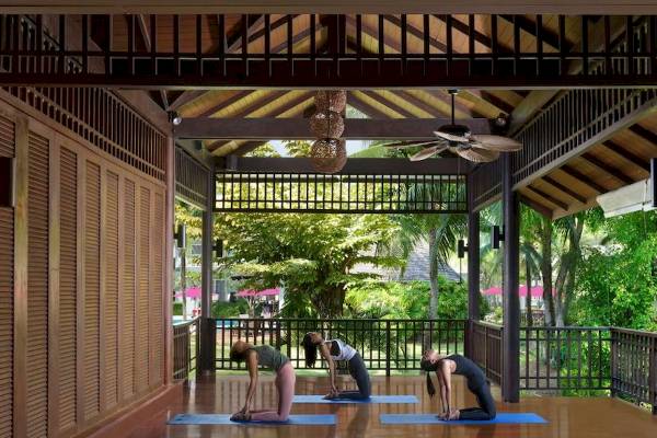 Yogakurs unter freier Luft im Aonang Villa Resort mit drei Frauen, die Yoga praktizieren.