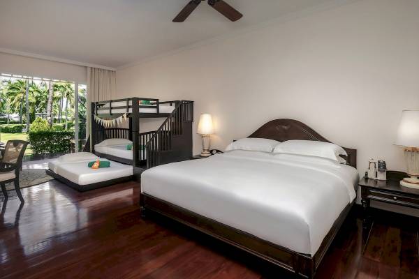 Schlafzimmer im Sofitel Krabi Phokeethra Golf & Spa Resort mit zwei Betten, Deckenventilator und Gartenblick.