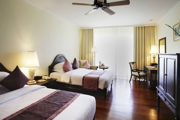 Doppelzimmer im Sofitel Krabi Phokeethra Golf & Spa Resort mit zwei Betten, Deckenventilator, Schreibtisch und Stühlen.