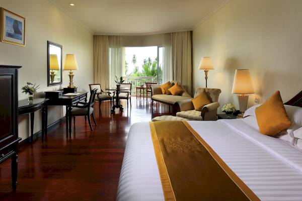 Ein elegantes Zimmer im Sofitel Krabi Phokeethra Golf & Spa Resort mit einem großen Bett, Möbeln und Ausblick auf eine Terrasse.