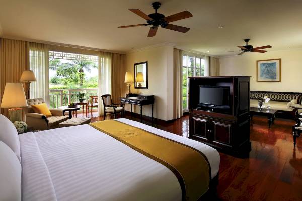 Innenansicht eines Hotelzimmers im Sofitel Krabi Phokeethra Golf & Spa Resort mit Bett, Fernseher, Schreibtisch und Balkon.