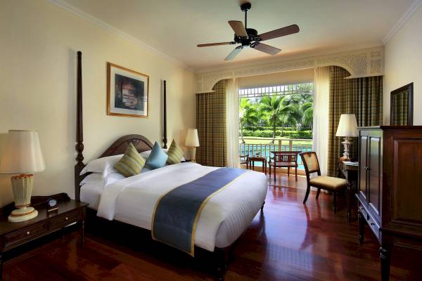Schlafzimmer im Sofitel Krabi Phokeethra Golf & Spa Resort mit großem Bett, Holzboden und Aussicht auf den Pool.