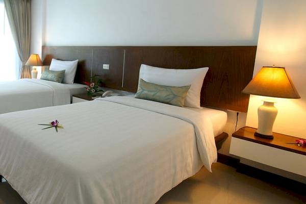Doppelbett-Zimmer im Peace Laguna Resort & Spa mit zwei Betten, Kissen, Lampen und einem Blumenarrangement.