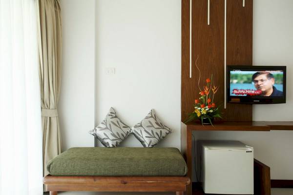 Zimmer mit Fernseher und Sofa neben einem Schreibtisch im Peace Laguna Resort & Spa.