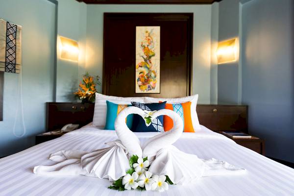 Ein Bett mit einem Schwanen-Arrangement aus Handtüchern und Blumen im Peace Laguna Resort & Spa.