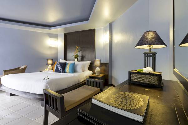 Ein stilvolles Hotelzimmer mit einem großen Bett, Tisch, Stühlen und Lampen im Peace Laguna Resort & Spa.