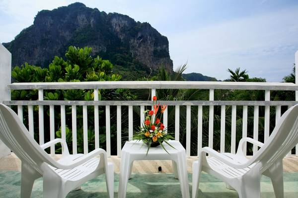 Blick auf einen Balkon des Peace Laguna Resort & Spa mit zwei weißen Stühlen und einer Blumenvase auf einem Tisch.