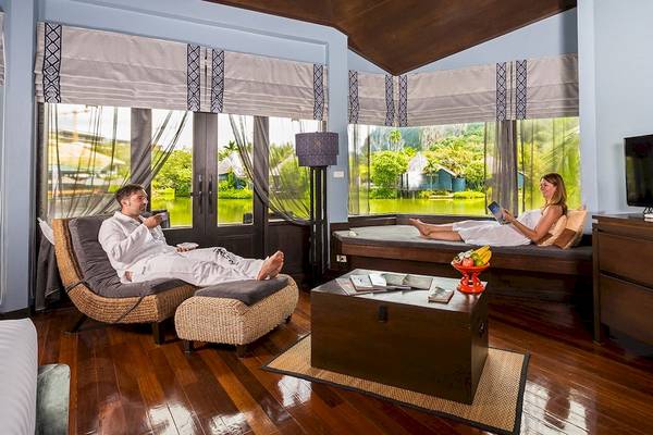 Ein Paar entspannt sich in einem stilvollen Zimmer des Friedens-Lagune-Resorts und Spas, mit einem Blick auf die Landschaft.