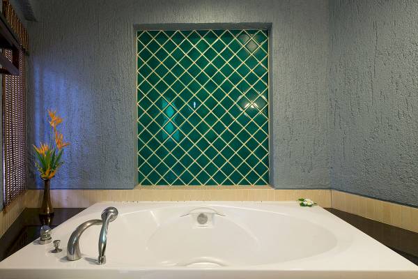 Badezimmer mit großer Badewanne und Blumenvase im Peace Laguna Resort & Spa