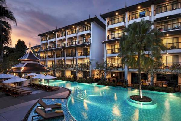 Abendlicher Blick auf das Centara Anda Dhevi Resort & Spa mit einem großen Swimmingpool und Lounge-Stühlen.