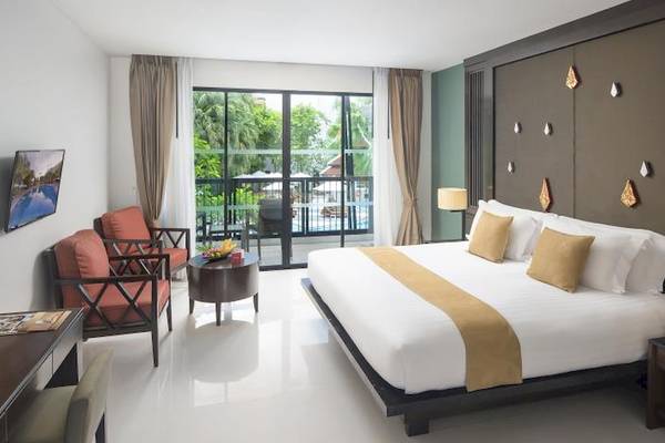 Hotelzimmer im Centara Anda Dhevi Resort & Spa mit Bett, Möbeln und Blick auf den Pool.