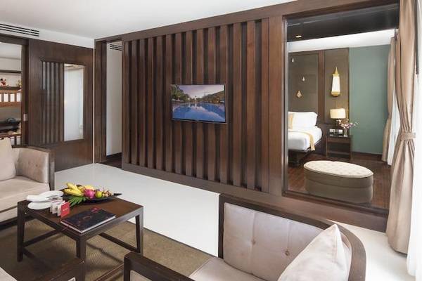 Innenansicht einer Suite im Centara Anda Dhevi Resort & Spa mit Couch, Tisch, Fernseher und Schlafzimmer.