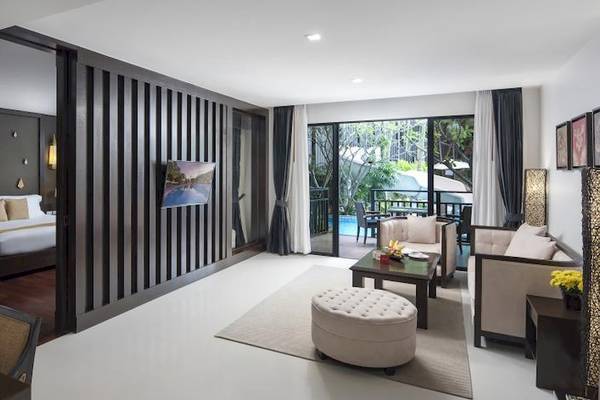 Innenbereich des Centara Anda Dhevi Resort & Spa mit Wohnzimmer, Bett, Fernseher, Couchtisch und Swimmingpool.