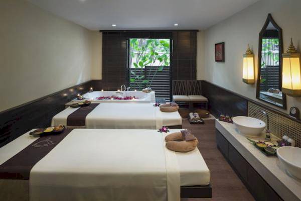 Massageraum im Centara Anda Dhevi Resort & Spa mit drei Massagebetten und einem Badewanne.