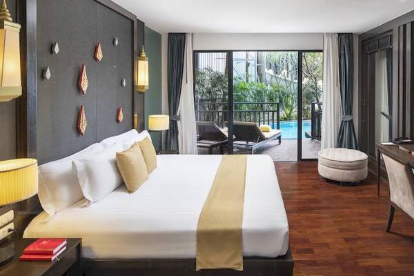 Hotelzimmer des Centara Anda Dhevi Resort & Spa mit großem Bett, Balkon und Poolblick.