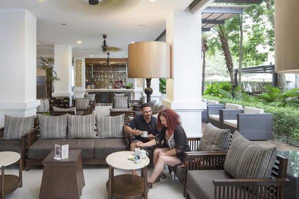 Paar im Empfangsbereich des Centara Anda Dhevi Resort & Spa, mit Möbeln und einer Bar im Hintergrund.