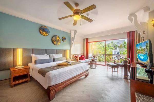 Innenansicht eines Zimmers im Chada Thai Village Resort mit großem Bett, Balkon und Fernseher.