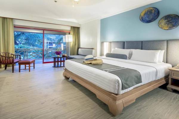 Zimmer des Chada Thai Village Resort mit Balkon, Bett und Wohnzimmermöbeln.