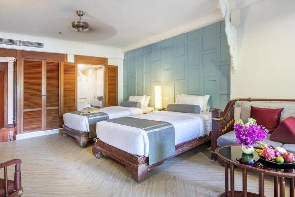Schlafzimmer im Chada Thai Village Resort mit zwei Betten, blauen Wänden und Holzmöbeln.