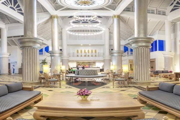 Lobby des Chada Thai Village Resorts mit modernen Möbeln, hohen Säulen und einer zentralen Sitzbank.