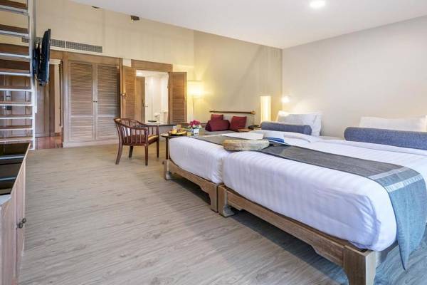 Doppelbett-Zimmer im Chada Thai Village Resort mit modernem Interieur und Holzmöbeln.
