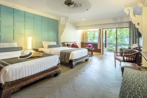 Ein Schlafzimmer im Chada Thai Village Resort mit zwei Betten und einem Balkon.