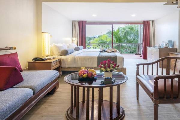 Hotelzimmer im Chada Thai Village Resort mit einem Bett, Tisch, Stühle und Aussicht auf einen Balkon.