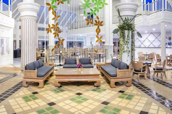 Hotellobbybereich mit Sofas, Tischen, dekorativen Wandschirmen und gefliestem Boden.