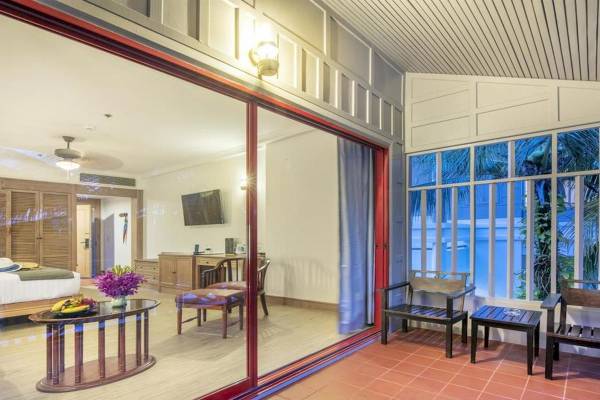 Aussicht auf das Zimmer im Chada Thai Village Resort mit großen Glastüren und Inneneinrichtung.