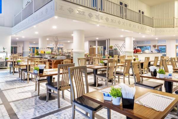 Innenansicht des Restaurants im Chada Thai Village Resort mit gepolsterten Stühlen und Tischen
