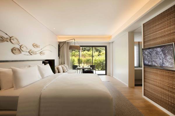 Schlafzimmer im The ShellSea Krabi mit Bett, Fenstern und Fernseher.