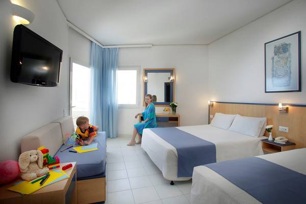 Hotelzimmer im Creta Princess Aquapark & Spa mit zwei Betten, Fernseher und Spielsachen.