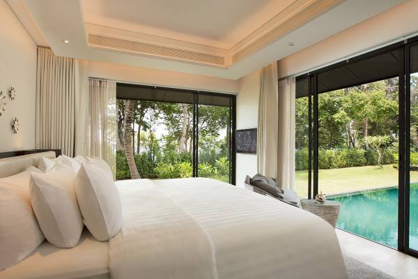 Schlafzimmer mit Bett und Blick auf den Pool im ShellSea Krabi Hotel.