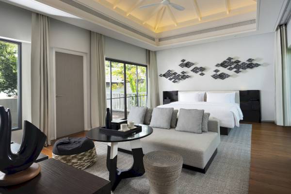 Das Schlafzimmer im ShellSea Krabi Hotel mit modernem Design, Doppelbett, Sofa, Tisch und Kunstwerken an der Wand.