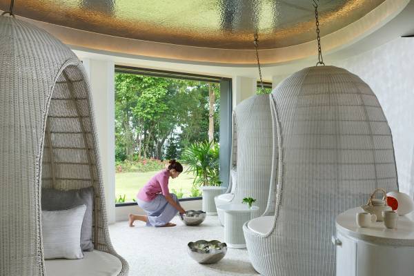 Eine Frau im ShellSea Krabi Hotel, die einen silbernen Wassereimer auf dem Boden holt.