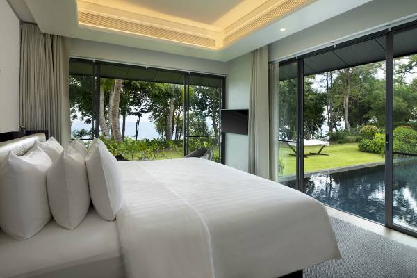 Luxuriöses Schlafzimmer im ShellSea Krabi Hotel mit Aussicht auf Pool und Meer.