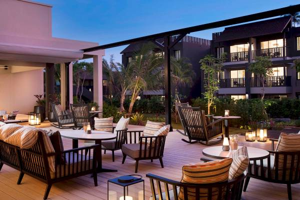Abendansicht des Loungebereichs im ShellSea Krabi Hotel mit gepolsterten Stühlen und Tischen auf der Terrasse.