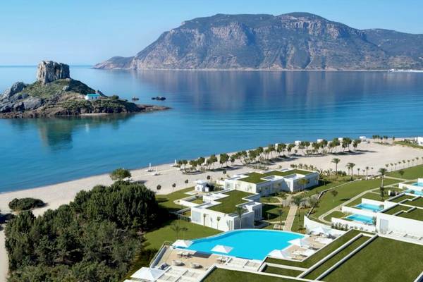 Ein Hotel am Strand mit Blick auf eine Felsinsel im Meer