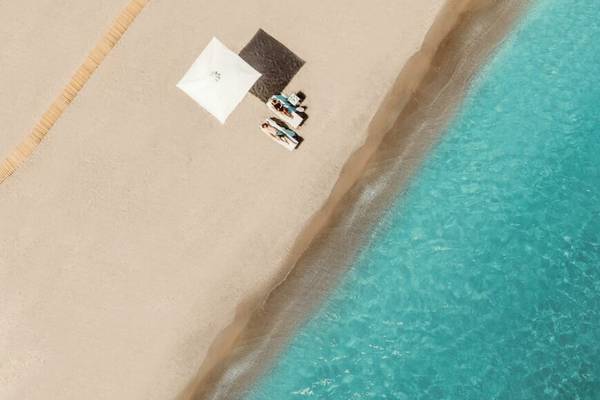 Ikos Aria Strand mit Sonnenliegen und Umbrella